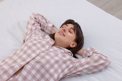 Photo of Beautiful woman lying on soft mattress at home, above view