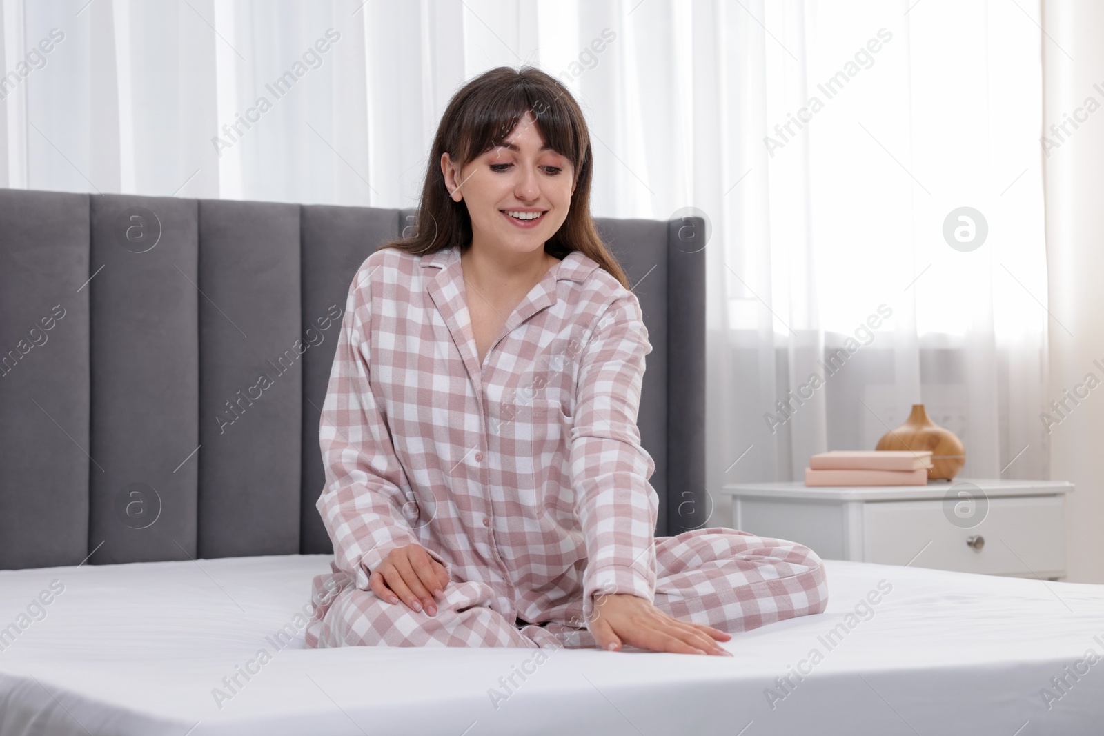 Photo of Beautiful woman sitting on soft mattress at home