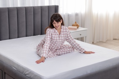 Photo of Beautiful woman sitting on soft mattress at home