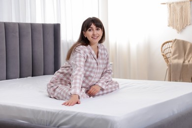 Photo of Beautiful woman sitting on soft mattress at home