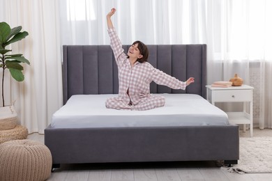 Photo of Smiling woman stretching on bed at home