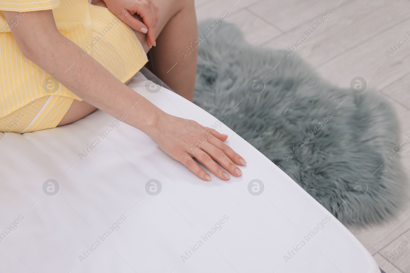Woman touching soft mattress on bed indoors, closeup Photo of Woman touching soft mattress on bed indoors, closeup