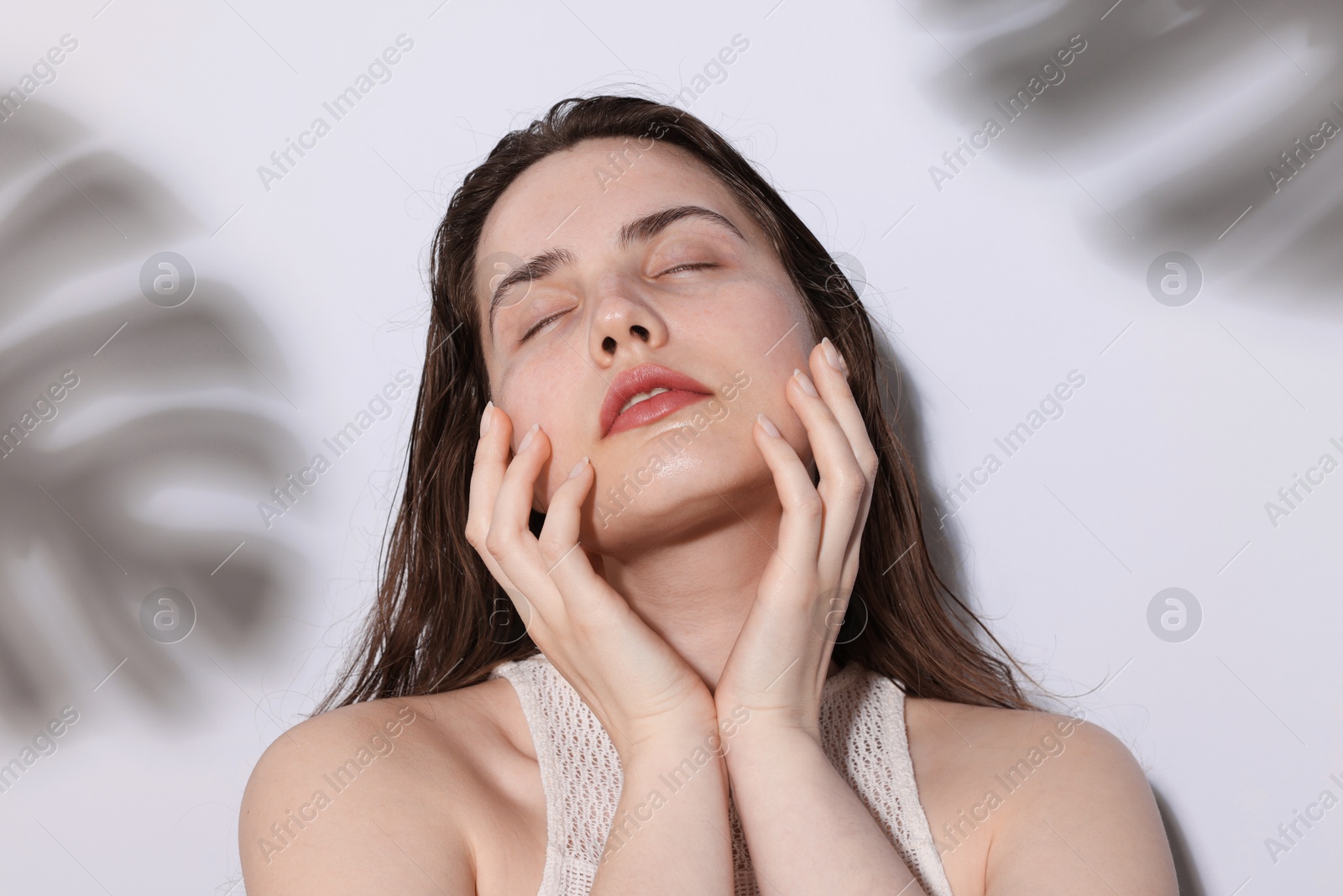 Photo of Beautiful woman with natural skin complexion on light background with shadows, closeup