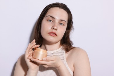 Photo of Portrait of beautiful woman with jar of skincare product on light background, closeup