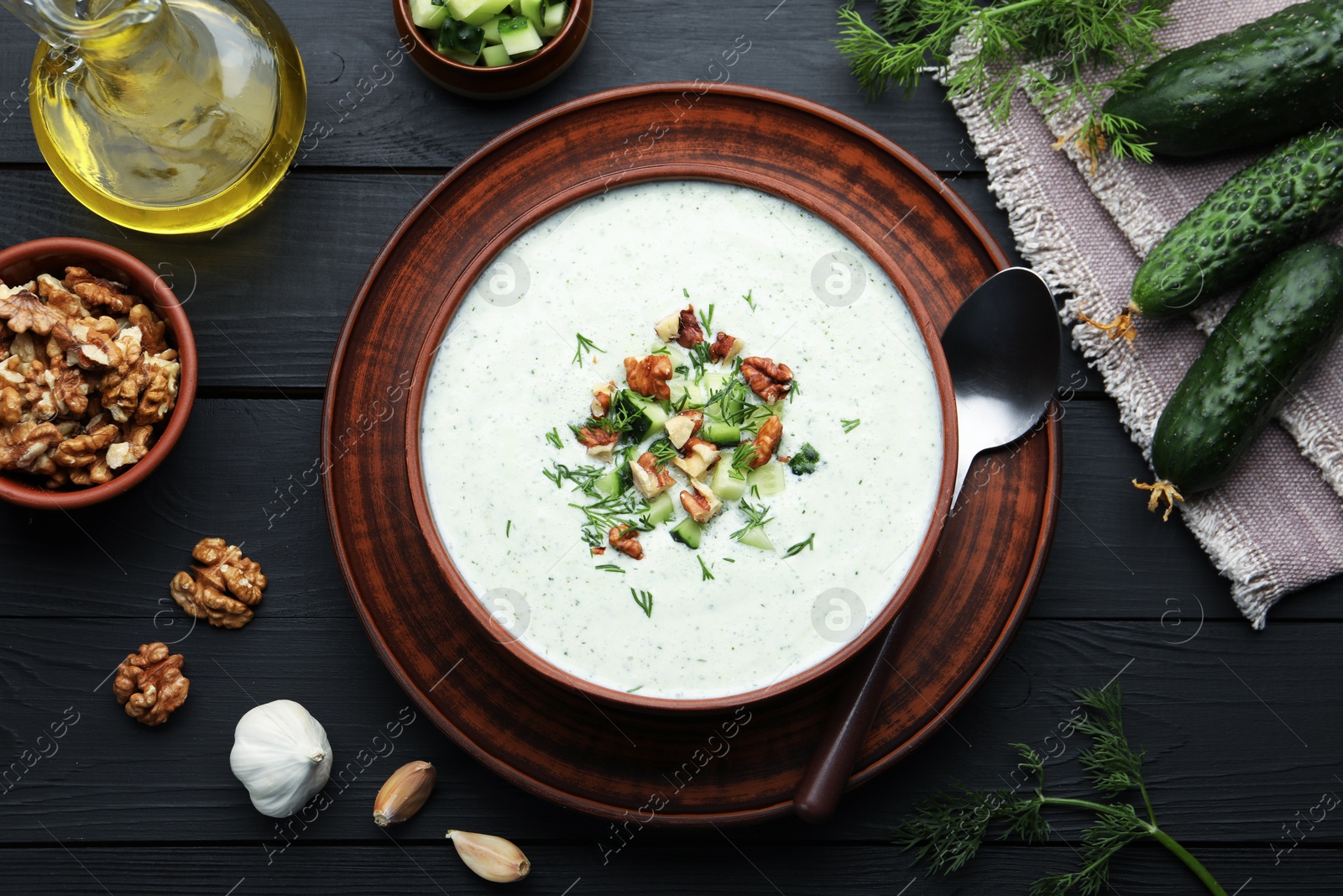 Tasty cucumber soup with dill and walnuts served on black wooden table, flat lay Photo of Tasty cucumber soup with dill and walnuts served on black wooden table, flat lay