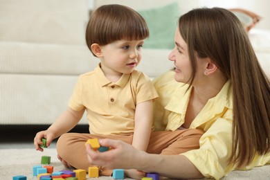 Photo of Mother and son playing with colorful cubes at home