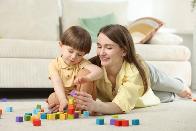 Photo of Mother and son playing with colorful cubes at home