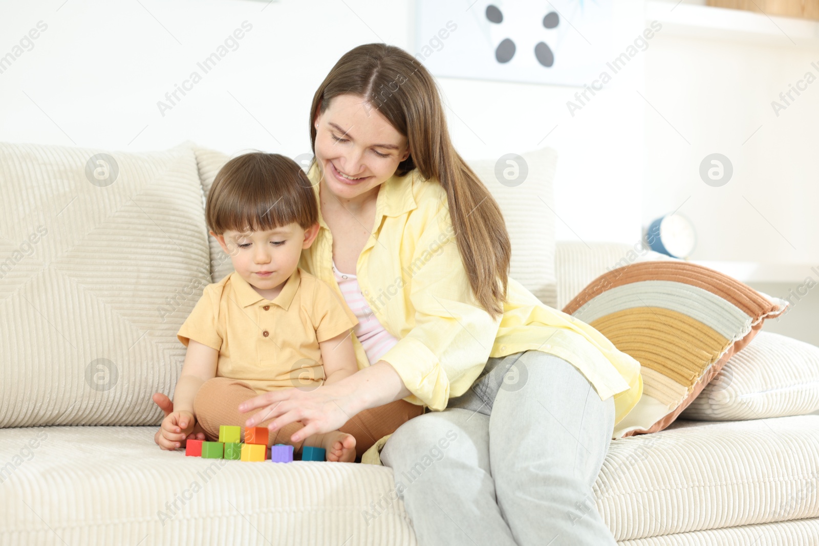 Mother and son playing with colorful cubes on sofa at home Photo of Mother and son playing with colorful cubes on sofa at home