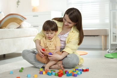 Photo of Mother and son playing with colorful cubes at home