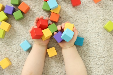 Photo of Cute little child playing with colorful cubes at home, above view