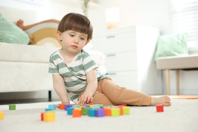 Photo of Cute little child playing with colorful cubes at home. Space for text