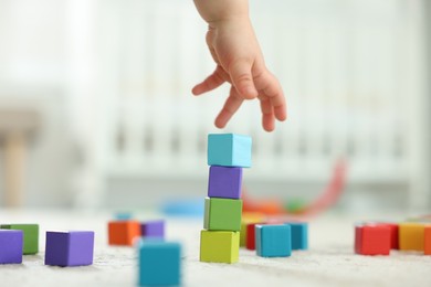 Photo of Cute little child playing with colorful cubes at home, closeup