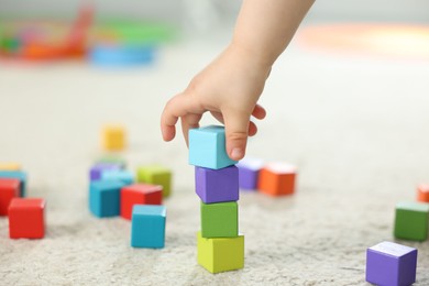 Photo of Cute little child playing with colorful cubes at home, closeup