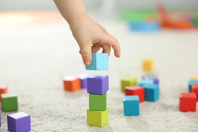 Photo of Cute little child playing with colorful cubes at home, closeup