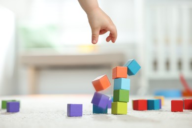 Photo of Cute little child playing with colorful cubes at home, closeup