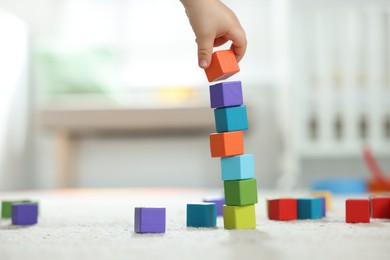 Photo of Cute little child playing with colorful cubes at home, closeup