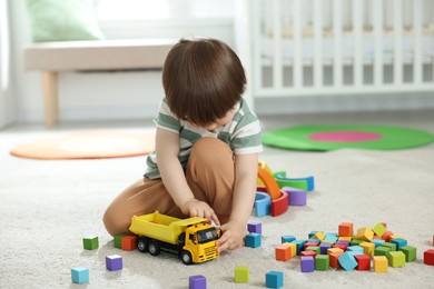 Photo of Cute little child playing with colorful cubes at home
