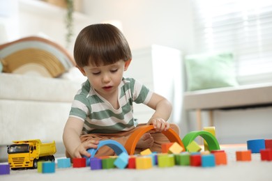 Photo of Cute little child playing with colorful cubes at home. Space for text