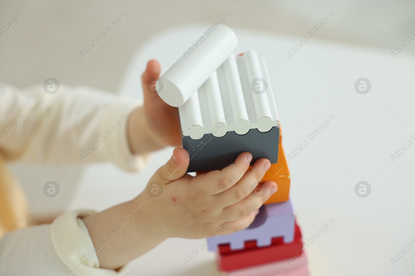 Cute little child playing with building bricks at white table indoors, closeup Photo of Cute little child playing with building bricks at white table indoors, closeup