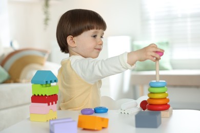 Photo of Cute little child playing with toys at table indoors
