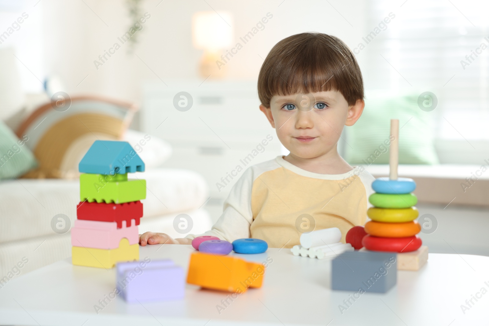 Cute little child playing with toys at table indoors Photo of Cute little child playing with toys at table indoors