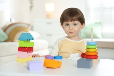 Photo of Cute little child playing with toys at table indoors