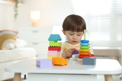 Photo of Cute little child playing with toys at table indoors