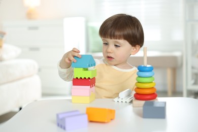 Photo of Cute little child playing with toys at table indoors