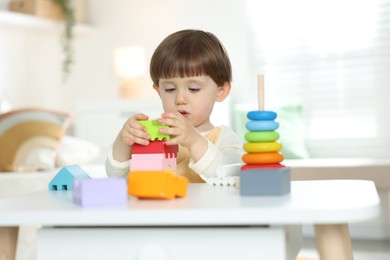 Photo of Cute little child playing with toys at table indoors