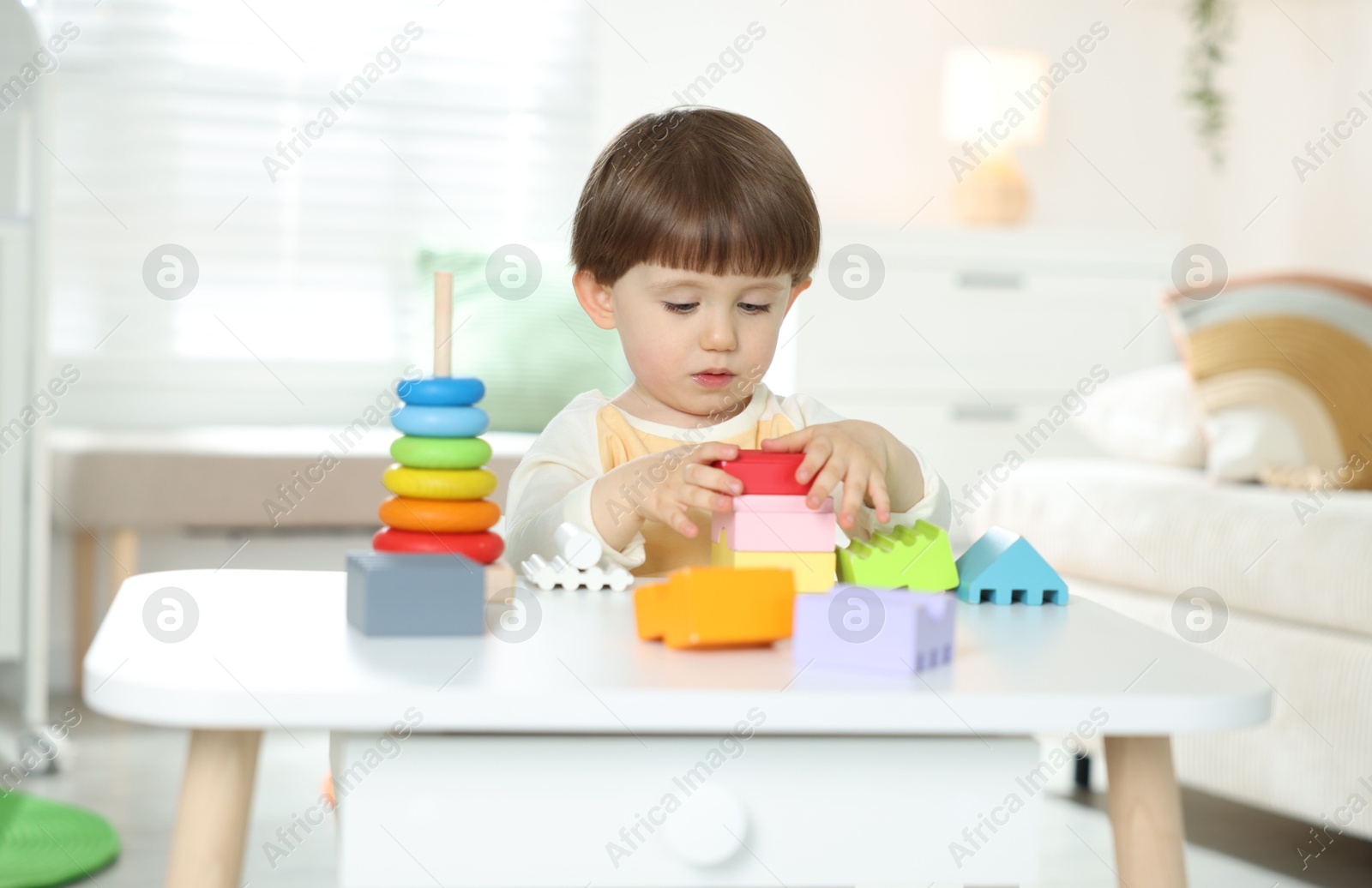 Cute little child playing with toys at table indoors Photo of Cute little child playing with toys at table indoors