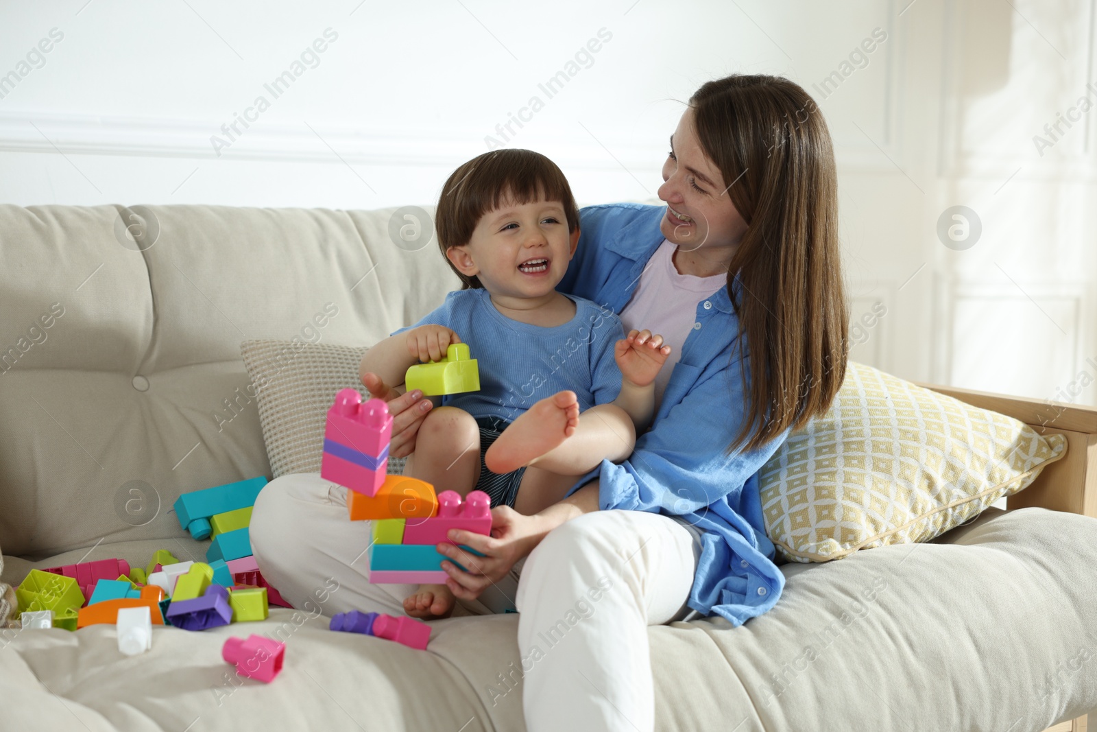 Mother and son playing with building bricks on sofa at home Photo of Mother and son playing with building bricks on sofa at home