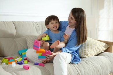 Photo of Mother and son playing with building bricks on sofa at home