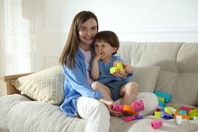 Photo of Mother and son playing with building bricks on sofa at home