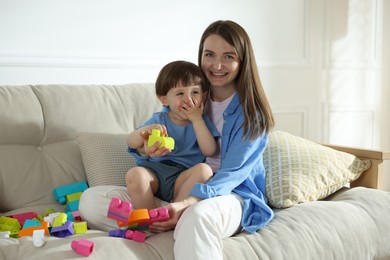 Photo of Mother and son playing with building bricks on sofa at home