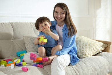 Photo of Mother and son playing with building bricks on sofa at home