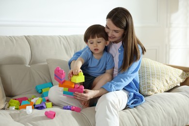 Photo of Mother and son playing with building bricks on sofa at home