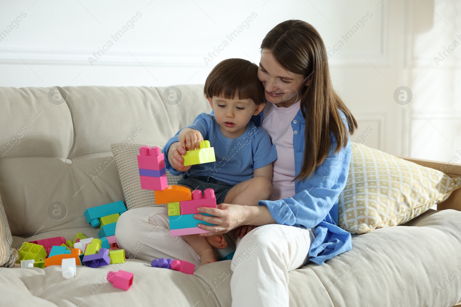 Mother and son playing with building bricks on sofa at home Photo of Mother and son playing with building bricks on sofa at home