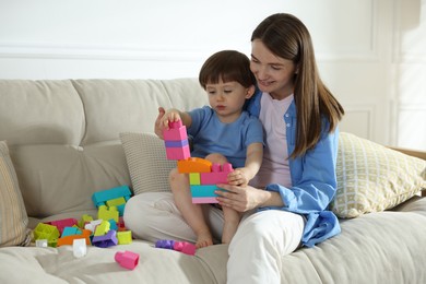 Photo of Mother and son playing with building bricks on sofa at home