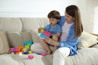 Photo of Mother and son playing with building bricks on sofa at home