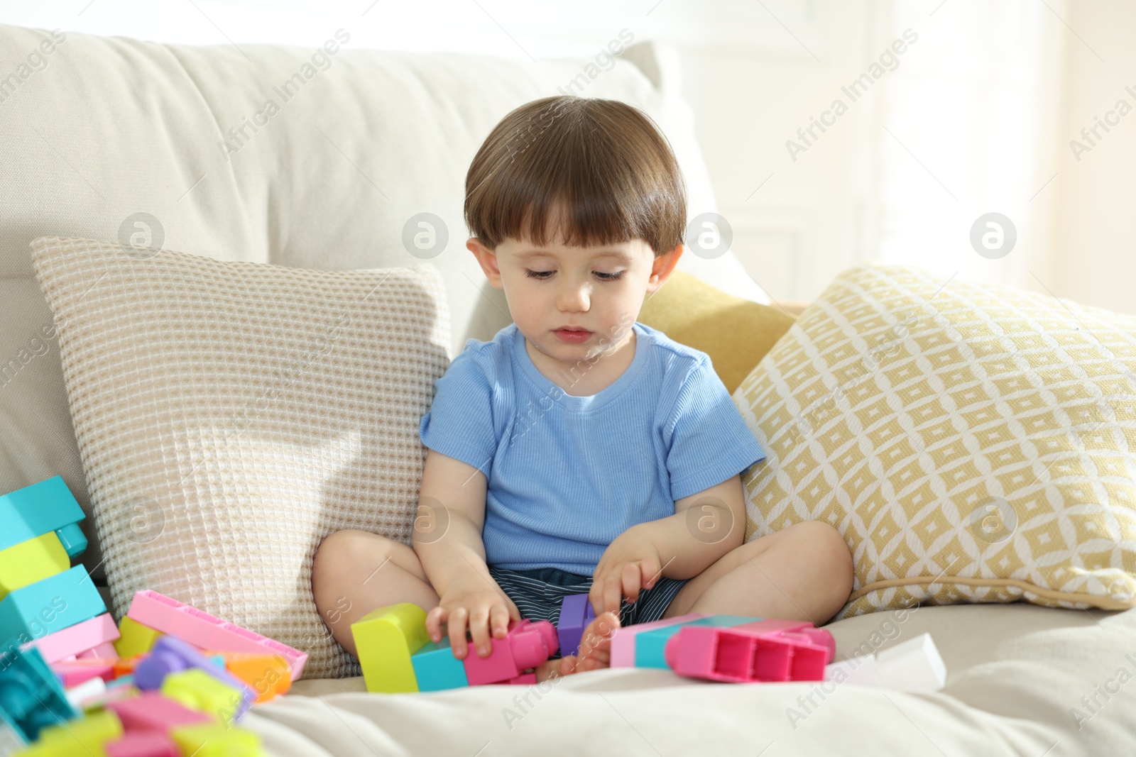 Cute little child playing with building bricks on sofa at home Photo of Cute little child playing with building bricks on sofa at home