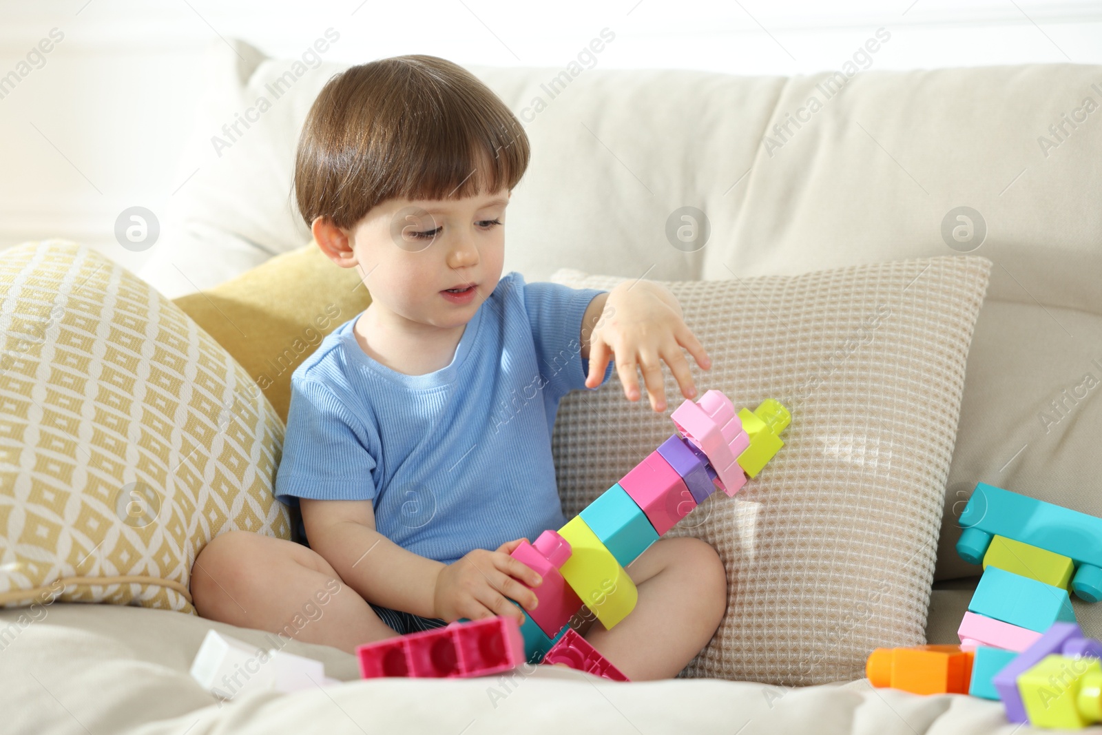Cute little child playing with building bricks on sofa at home Photo of Cute little child playing with building bricks on sofa at home