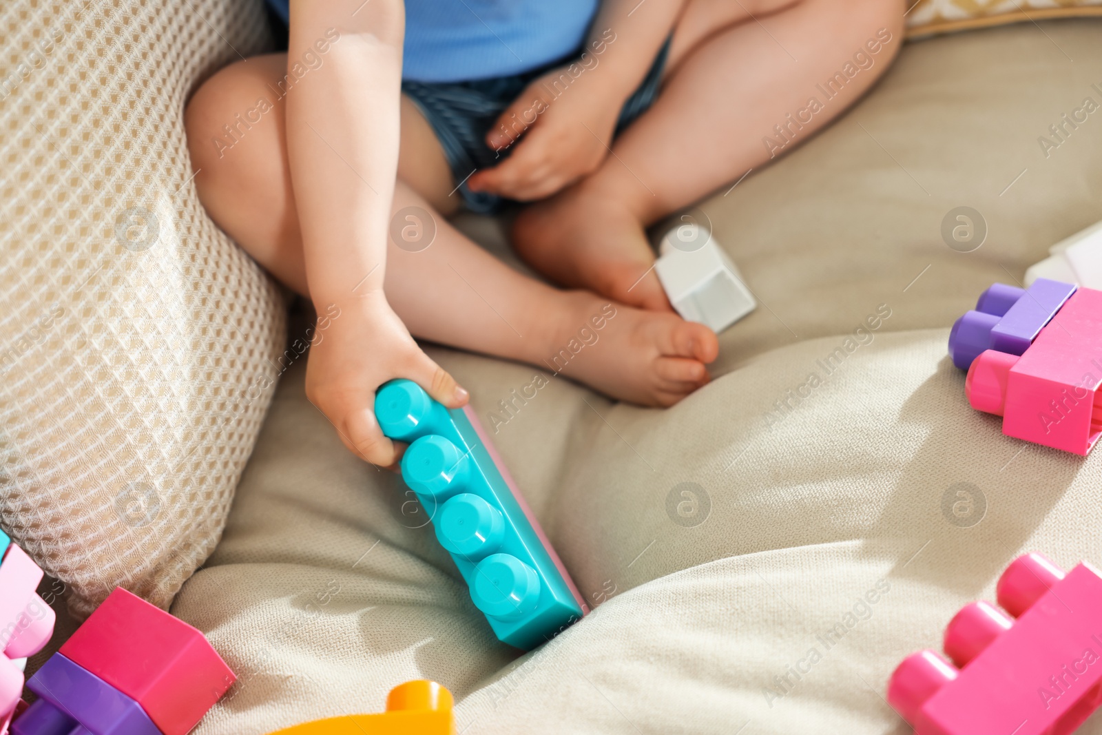 Cute little child playing with building bricks on sofa at home, closeup Photo of Cute little child playing with building bricks on sofa at home, closeup