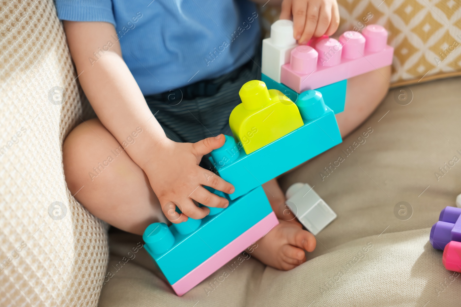 Cute little child playing with building bricks on sofa at home, closeup Photo of Cute little child playing with building bricks on sofa at home, closeup