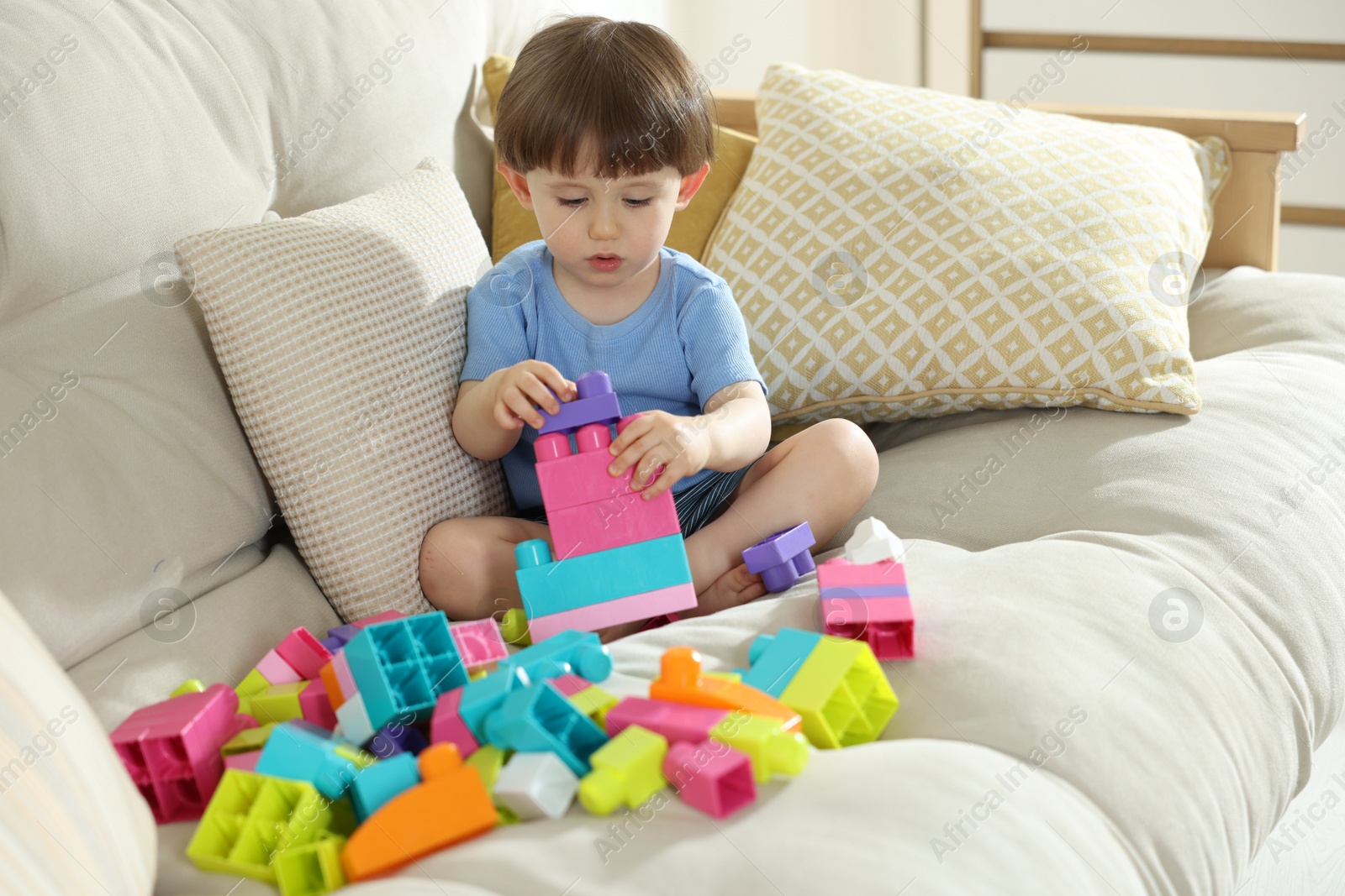 Cute little child playing with building bricks on sofa at home Photo of Cute little child playing with building bricks on sofa at home