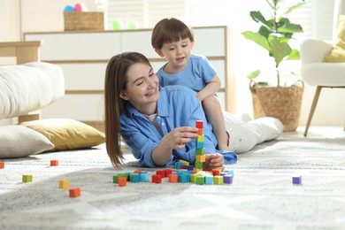 Photo of Mother and son playing with colorful cubes at home