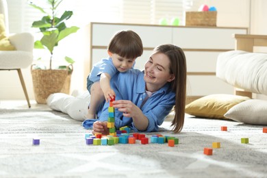 Photo of Mother and son playing with colorful cubes at home