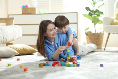 Photo of Mother and son playing with colorful cubes at home