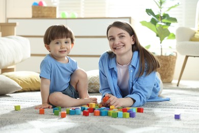 Photo of Mother and son playing with colorful cubes at home