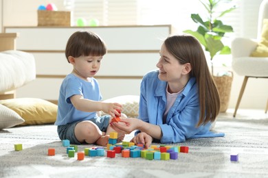 Photo of Mother and son playing with colorful cubes at home