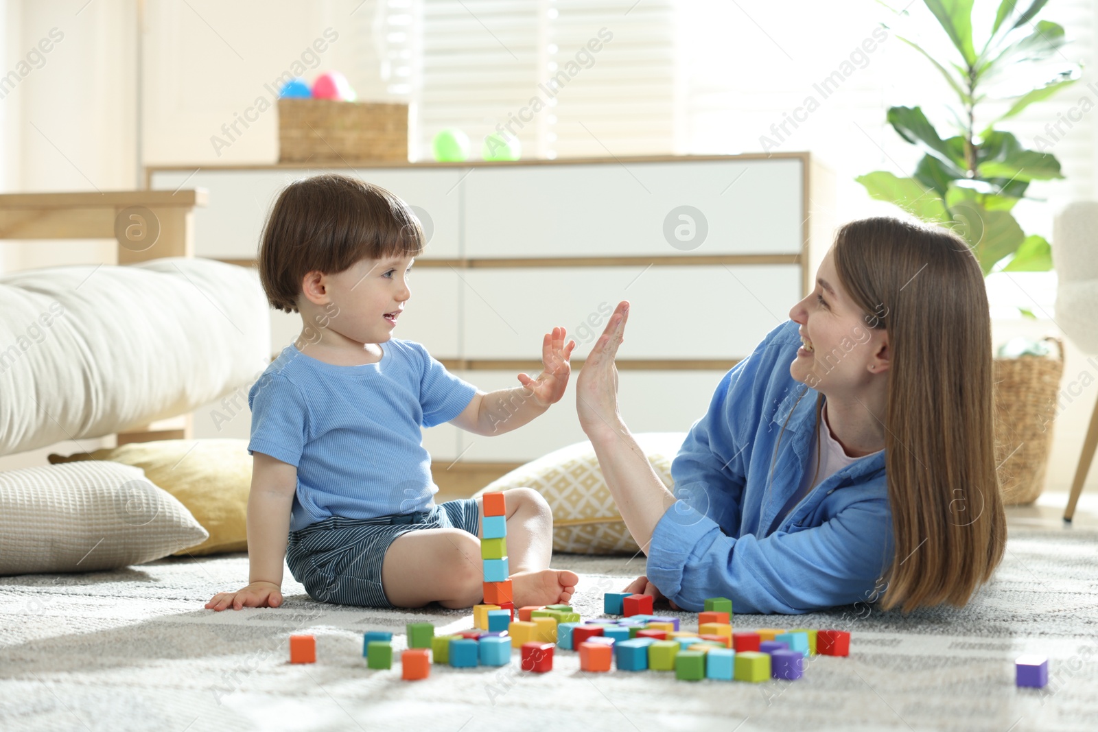 Mother and son giving high five while playing with colorful cubes at home Photo of Mother and son giving high five while playing with colorful cubes at home